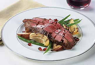 Pomegranate glazed flank steak on potato wedges and beans